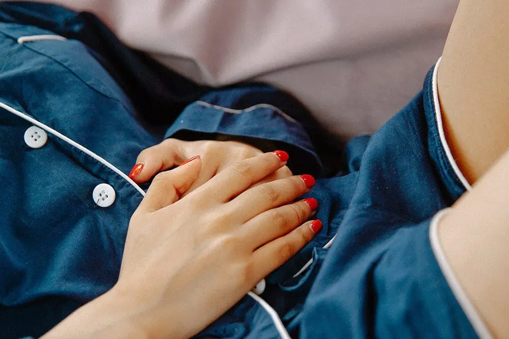 zakażenia układu moczowego: Kobieta trzyma ręce na brzuchu