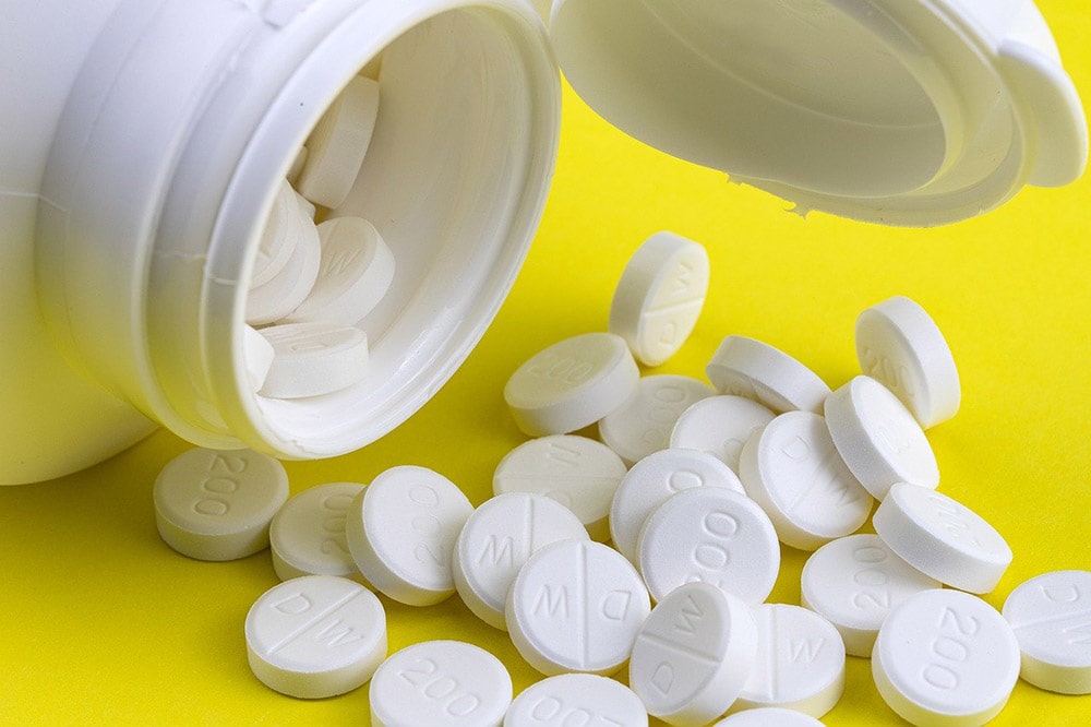 Leki psychotropowe w postaci białych pigułek na żółtym stole