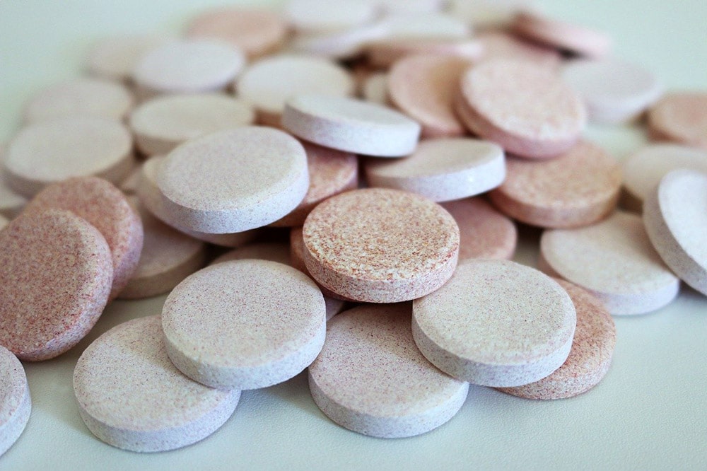 Aspiryna: Białe i różowe tabletki na białym stole