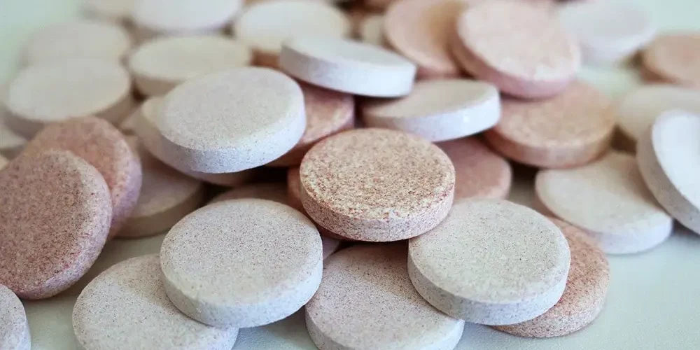 Aspiryna: Białe i różowe tabletki na białym stole