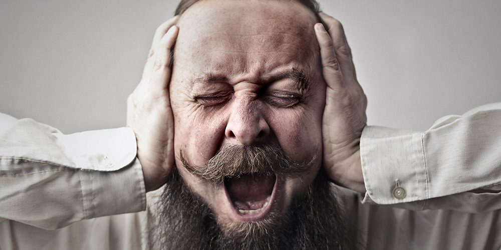 Ból ucha: Facet trzyma ręce na uszach i krzycy