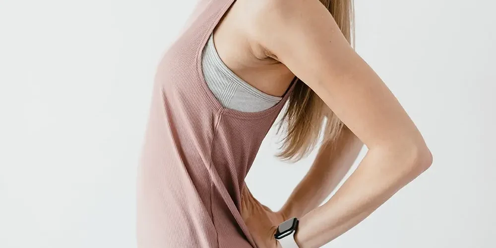 Lady wearing a beige T-shirt. You have a pain in the sacroiliac joint and she keeps her hands in this place