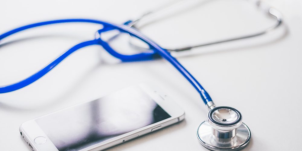 Migrena: Biały stół, na którym są fonendoskop i telefon