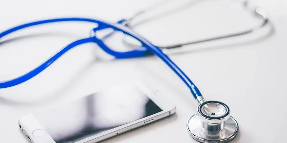 Migrena: Biały stół, na którym są fonendoskop i telefon