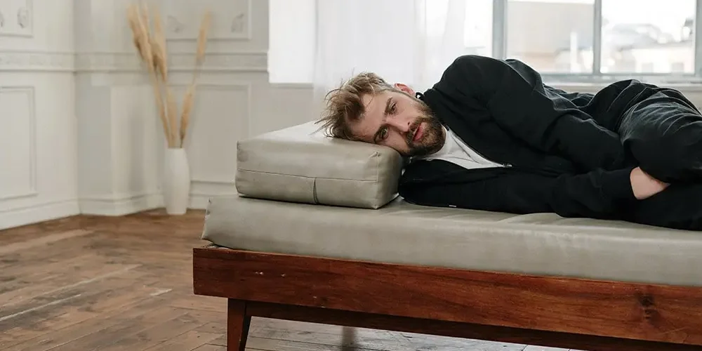 Prostatitis: A man in black clothes with prostatitis is lying on the bed