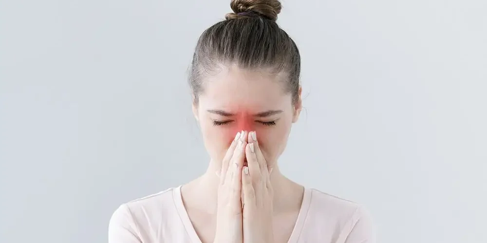 Pani trzyma ręce na nosie, ma zapalenie zatok